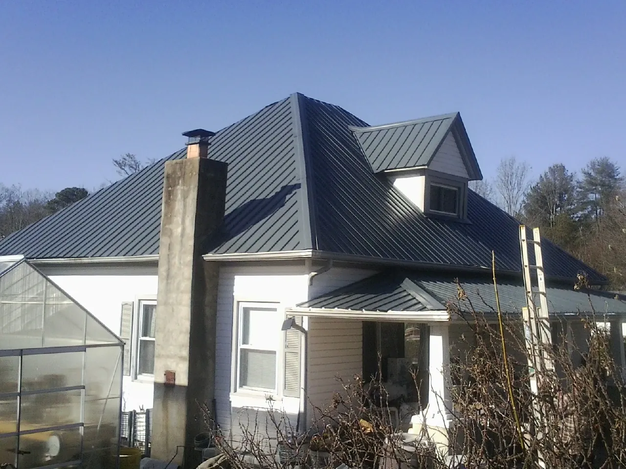 Dark blue standing seam metal roof on a white farmhouse with dormer — Slate & Tile Roof Repair by Roofing Brothers in Berrien Springs