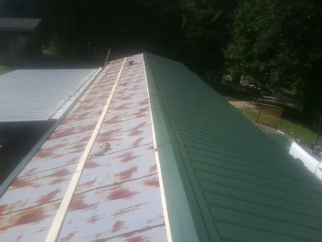 Old rusted panels beside newly installed green metal roofing — Wind Damage Roof Repair by Roofing Brothers in Berrien Springs