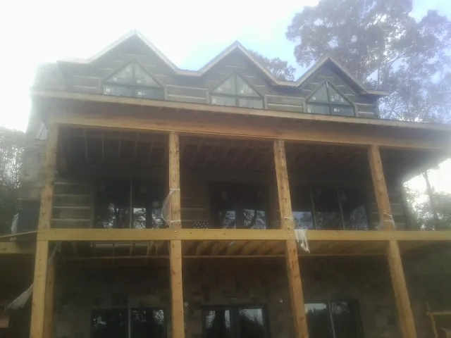 Dormers and porch framing on a large log home under construction — Roof Coating work by our crew in Berrien Springs