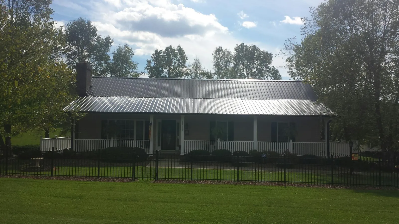 Gray metal roof on a brick ranch with a full width front porch — Gutter Guard Installation work by our crew in Berrien Springs