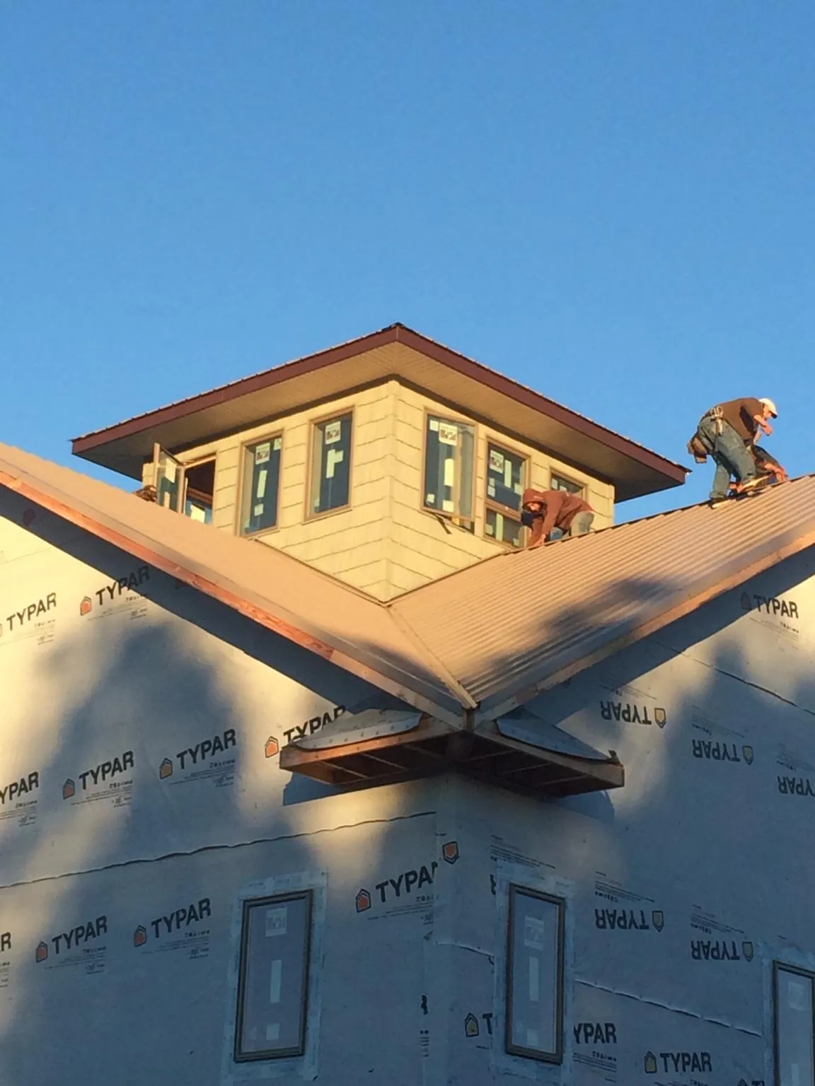 Roofers working around a rooftop cupola on a new metal roof at sunset — Roof Waterproofing in Berrien Springs by Roofing Brothers